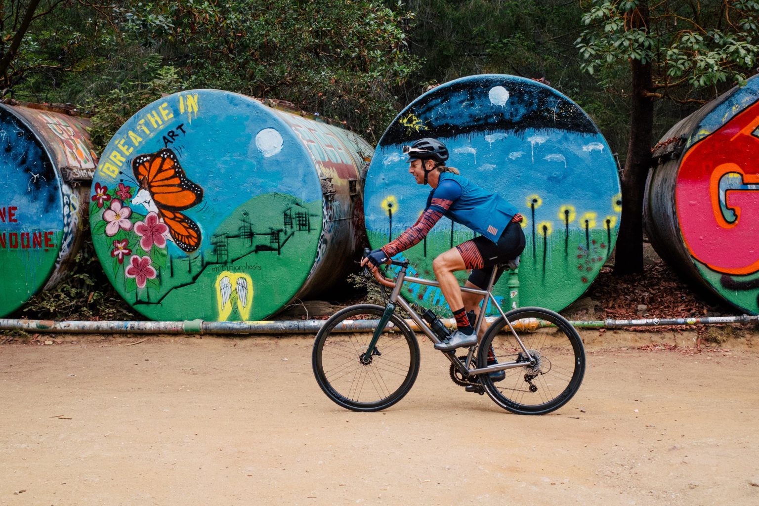 A titanium gravel bike riding past the 'barrels' at UCSC